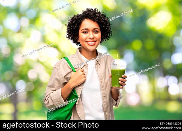 woman with reusable shopping bag drinking smoothie
