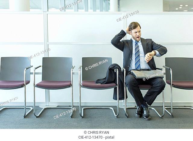 Businessman checking wristwatch in waiting area