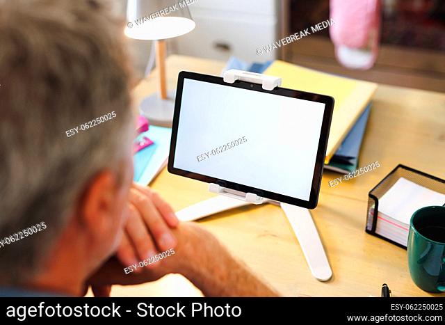 Caucasian man sitting at table in kitchen and using tablet with copyspace