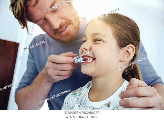 Father brushing daughterâ€™s teeth in bathroom