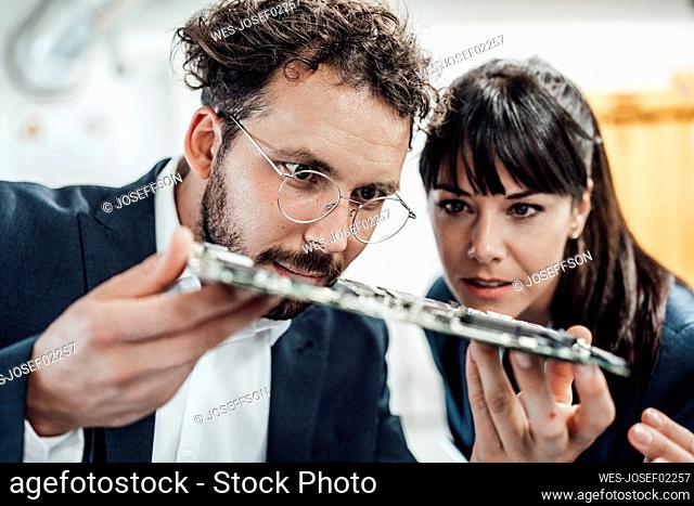Business colleagues examining circuit board at industry