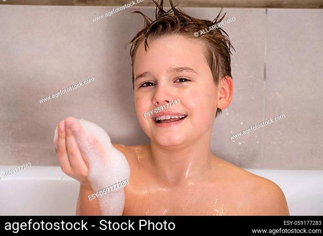 Portrait of funny boy playing with water and foam in a bathroom Cute happy child bathe at home healthy childhood