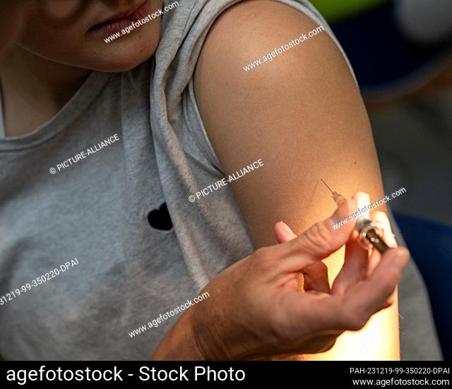 PRODUCTION - 12 December 2023, Bavaria, Planegg: Gynecologist Stephanie Eder gives an injection into the upper arm of a teenager during the HPV vaccination in a...