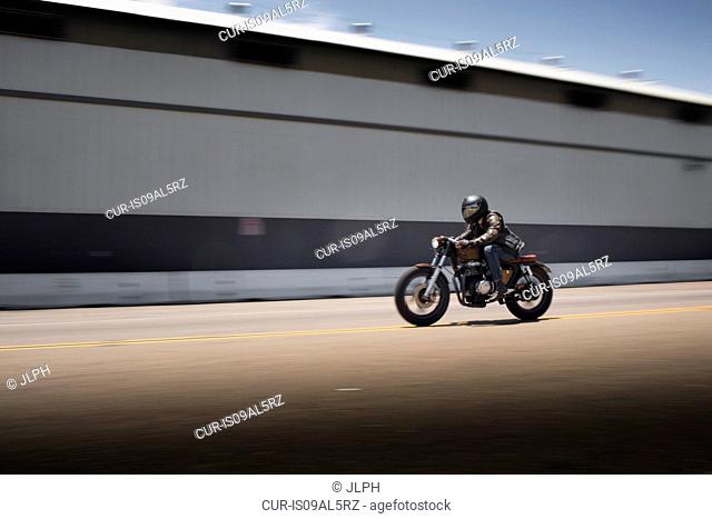 Blurred image of speeding male motorcyclist
