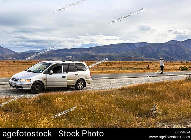 Guy with camera next to car, Omarama, Waitaki District, Canterbury, South Island, New Zealand, Oceania