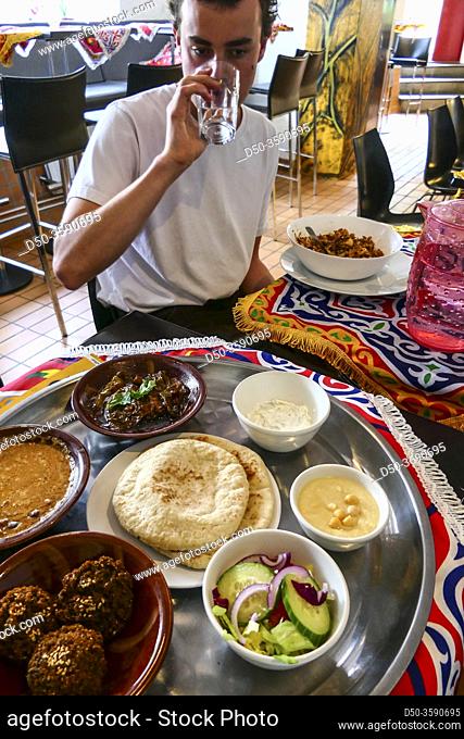 Gothenburg, Sweden July 15, 2020 A man with a selection of hummus, falafel, salad, foul, and pita bread at an Egyptian restaurant