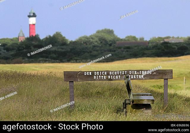 Note on dike protection on a wooden bench, view of the old lighthouse of Wangerooge, Lower Saxony