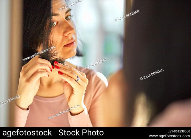 Problem damaged hair concept, Pretty Brunette woman brushing hair with comb in front of the mirror at the morning at home, sunlight,