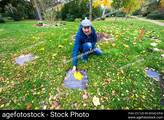 PRODUCTION - 09 November 2023, Lower Saxony, Lüneburg: Hans Hockemeyer, cemetery manager in Lüneburg, kneels at a so-called tree grave