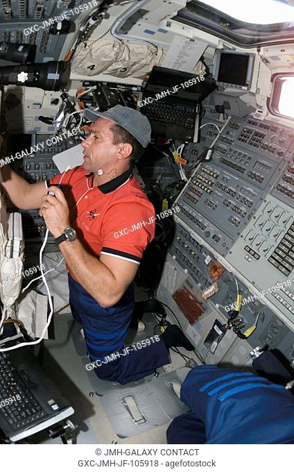 Astronaut William A. (Bill) Oefelein, STS-116 pilot, uses a communication system while looking at a procedures checklist (out of frame) on the aft flight deck...