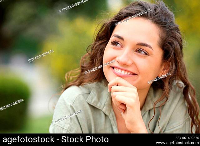 Pensive woman looks at side wondering in a park