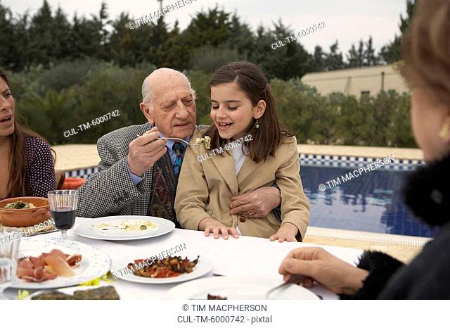 Three generation family eating outdoors