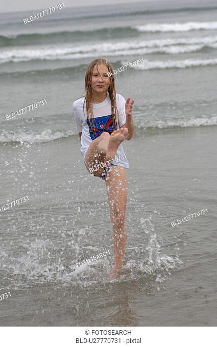 Girl kicking her leg in water, Wickaninnish Beach, Vancouver Island, Canada