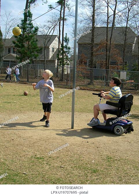 A boy, who uses a wheelchair, watches one of his friends play tether ball