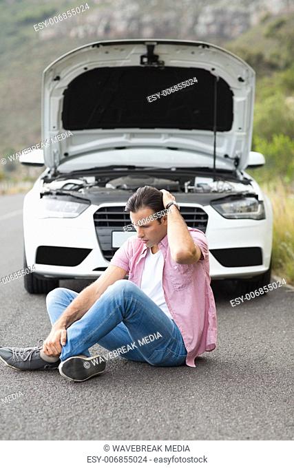 Stressed man sitting after a car breakdown