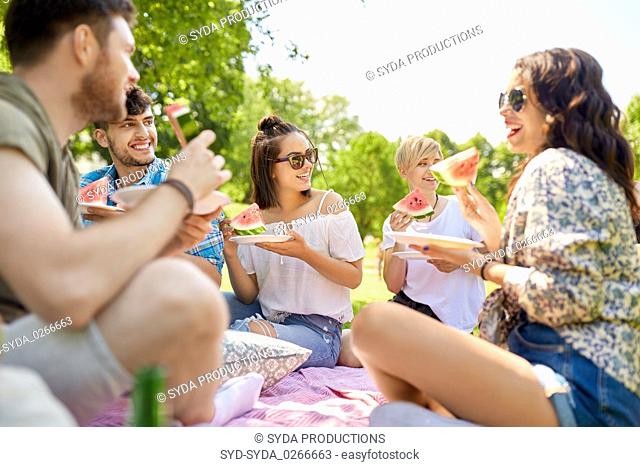 happy friends eating watermelon at summer picnic