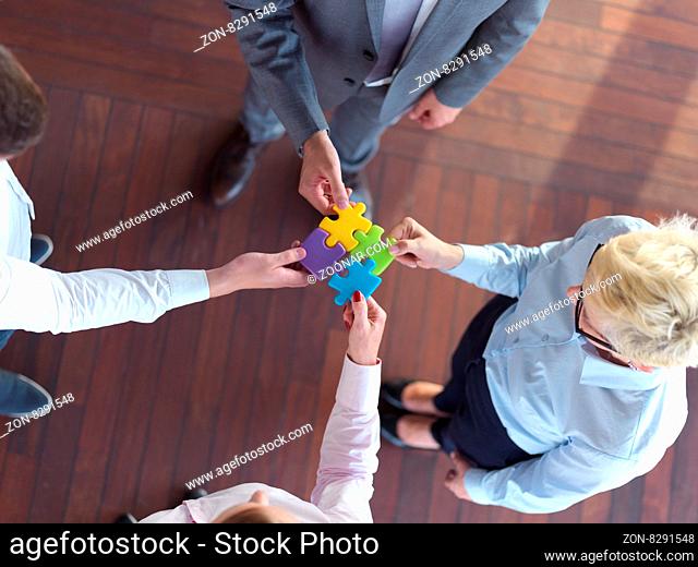 business people group assembling jigsaw puzzle and represent team support and help concept, top view at modern office interior