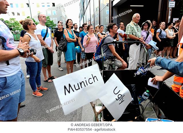 Around 100 participants listen to the London-born and Vienna-based city guide, Eugene Quinn, during the first 'Munich Ugly Tour' in downtown Munich,  Germany