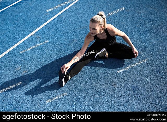 Young athlete doing warm up exercise on track