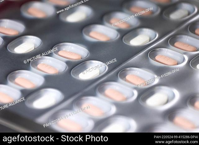 24 May 2022, Baden-Wuerttemberg, Freiburg im Breisgau: Tablets of the drug Paxlovid for the treatment of Covid-19 pass through a packaging line in a building...