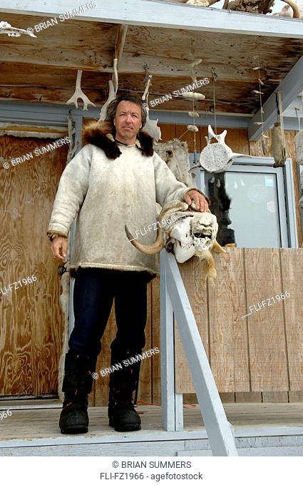 Man with Musk Ox Skull on porch, Cambridge Bay, Nunavut