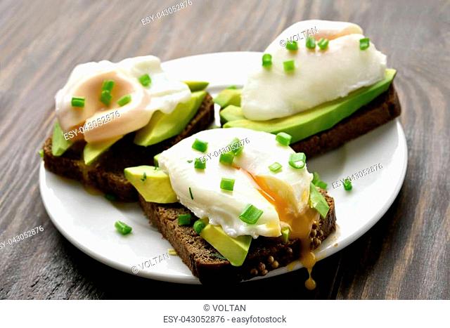 Poached eggs and avocado on bread, close up view