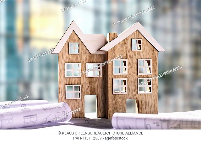 Two wooden houses with blueprints in front of office scene | usage worldwide