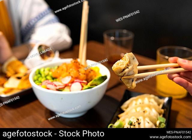 Female friends eating food with chopsticks at restaurant