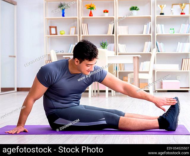 Young man exercising at home in sports and healthy lifestyle concept