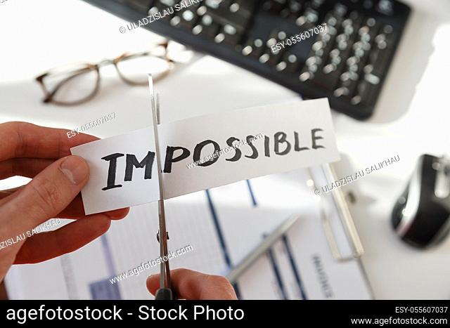 Businessman hands cutting the word impossible, letters im so it become possible. Success and motivation concept. On white
