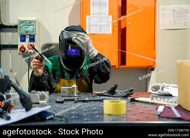 A woman employed in a modern factory for the production and processing of metals in a work uniform welding metal materials. High quality photo