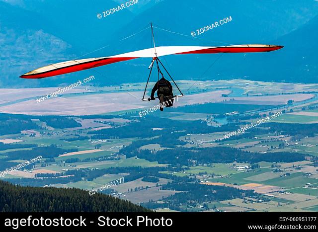 Hang gliding in action. Hang Glider pilot launching over the Kootenay valley mountains, Creston, British Columbia, Canada
