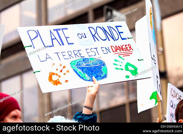 A protestor holds a French sign with the phrase flat or round, the earth is in danger during a crowded street protest against climate change