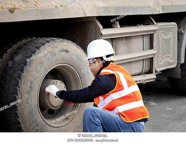 Construction worker checking tyre truck