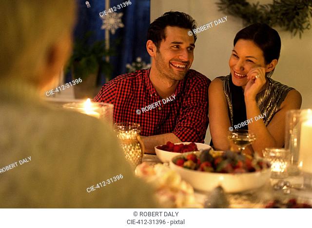 Smiling couple enjoying candlelight Christmas dinner