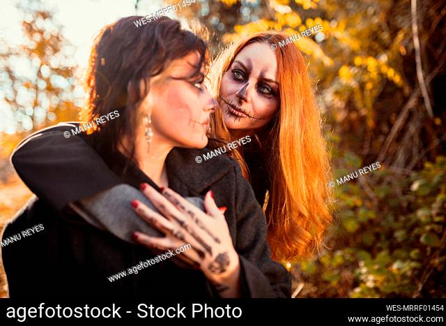 Woman with Halloween make-up looking at friend in forest