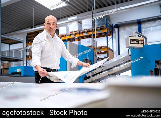 Businessman in a printing plant holding paper