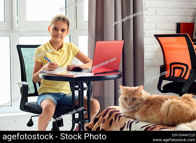 Schoolgirl at table at home studying remotely online