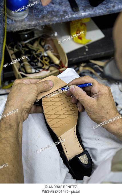 Shoemaker marking the sole of a shoe with a pencil