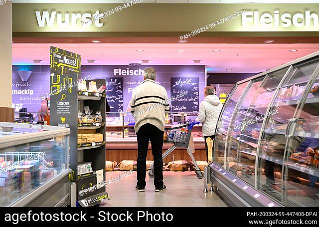 24 March 2020, Baden-Wuerttemberg, Stuttgart: Customers are standing at a distance in front of the meat counter in a branch of Edeka Fleck in the Fasanenhof...