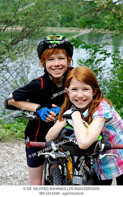 Two children, boy and girl, with mountain bikes and helmets
