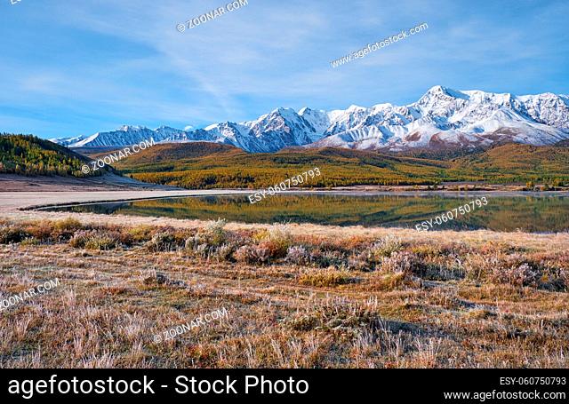 View on Altai lake Dzhangyskol on mountain plateau Eshtykel. North Chui ridge is on background. Grass is covered by hoarfrost. Altai, Siberia, Russia