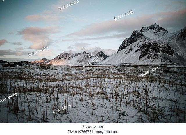 A snowy field in front of some mountains in Stokksnes, Iceland