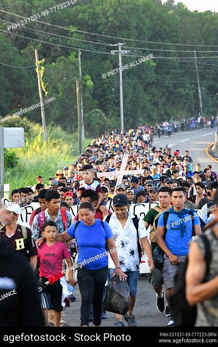 31 October 2023, Mexico, Chiapas: People carry a cross and continue north along the side of a highway hoping to cross Mexico and enter the United States