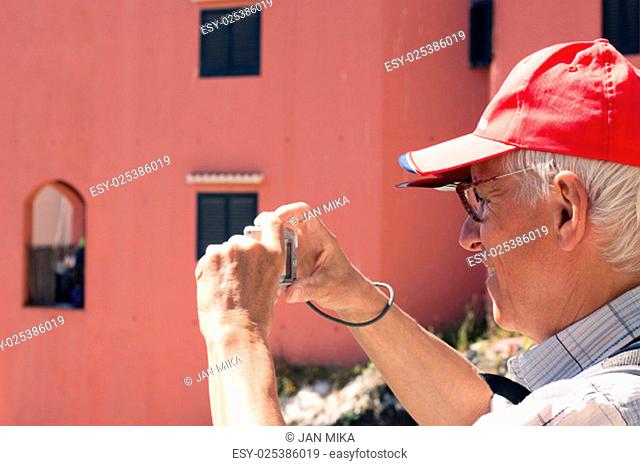 Senior man tourist taking photos using compact camera