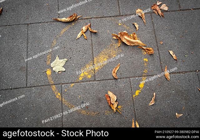 27 September 2021, Lower Saxony, Osnabrück: A faded pictogram with a syringe on it can be seen on the pavement in front of the vaccination centre of the city of...