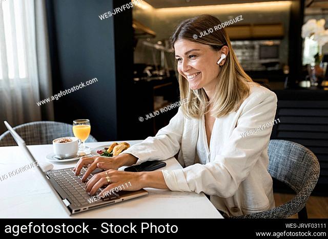 Happy businesswoman using laptop at restaurant