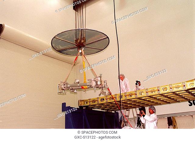 02/25/1999 --- At Astrotech, Titusville, Fla., three workers watch as the overhead crane lifts and moves the ORU Transfer Device OTD to the top of the...