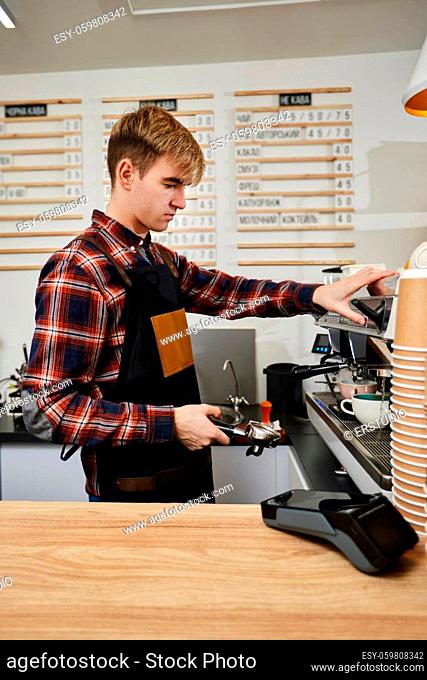 young barista wearing aprons preparing coffee using a coffee machine in cafe