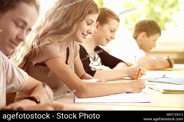 Students or pupils or mates writing a examination or test in a classroom or school or class